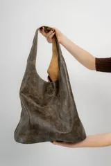 Maxi cartera tipo bolso de cuero natural, con base plana y diseño simple sin metales.