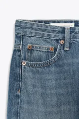 Jeans de tiro alto con pierna ancha y largo completo. Confeccionados en tejido rígido con cinco bolsillos, cintura con trabillas, detalle de costuras torcidas y cierre con cremallera y botón metálico.
