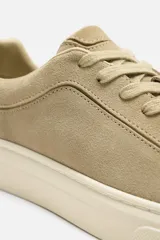 Zapatillas bajas color beige de piel serraje con cordones y suela plana color crema.