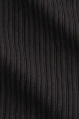 Remera ajustada de punto acanalado suave, color negro, con cuello redondo ribeteado en picot y tapeta de botones. Manga larga.