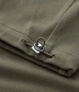 Blusa verde militar en suedine texturizada, con cuello redondo, manga larga con recortes y tiradores en los puños.