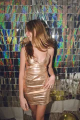 Vestido plateado con corte bajo el busto, abertura en la cintura y espalda descubierta. Se ata al cuello con dos tiras finas.