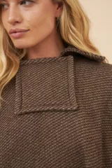 Poncho unisex de lana color marrón con cuello alto y broche a presión. Diseño exclusivo de Don Baez, hecho en Uruguay.