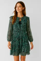 Vestido corto color verde con estampado floral, escote en V con borla, mangas largas abullonadas y falda escalonada con volantes.