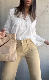 Blusa blanca de algodón con bordado broderie, escote en V y mangas largas.
