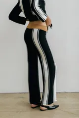 Pantalón de punto color crudo con rayas verticales negras a los costados.