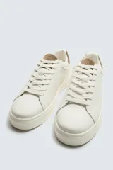 Zapatillas deportivas blancas con detalle de color marrón en el talón y suela con volumen.