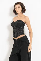 Corset negro con copas preformadas, ballenas y cierre trasero con ganchos. El cuerpo del corset está confeccionado en tejido con lentejuelas dispuestas en forma de chevron.