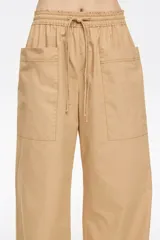Pantalón corte jogger color beige, con largo tobillero, bolsillos tipo alforja y logo bordado. Cintura elástica ajustable con cordones.