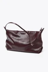 Bolso bandolera tipo sobre color borgoña, con asa fina y cierre imantado con solapa. Incluye bolsillo interior con cierre de cremallera metálica.