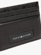 Tarjetero de cuero negro con múltiples ranuras para tarjetas y logo metálico de Tommy Hilfiger en el frente.