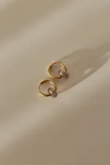 Par de aros dorados tipo argolla con dije de piedra natural color lila.