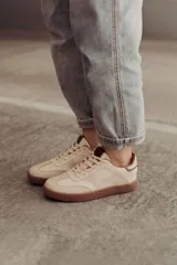 Zapatillas bajas de cuero color marrón con suela de goma color caramelo y cordones marrones.