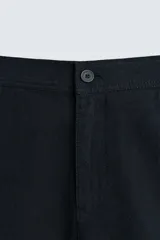 Bermuda azul marino de corte regular, confeccionada en tejido de algodón y lino. Cuenta con bolsillos frontales y traseros, y cierre frontal con cremallera y botón.