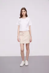 Minifalda color beige con botones plateados al frente y bolsillos delanteros.