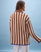 Cárdigan tejido a rayas verticales color beige y marrón, con cuello marrón y detalles en azul. Cierre frontal con nudos y bolsillos delanteros.