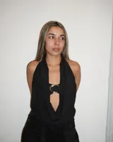 Top negro con escote halter y abertura en el centro del pecho unida por un aro dorado.