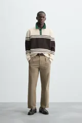 Polo de hombre relaxed fit, tejido en hilatura con textura chenilla. Presenta cuello solapa con cierre frontal de botonadura, manga larga y acabados en rib. Diseño a rayas horizontales en color crema y negro, con cuello en verde oscuro.