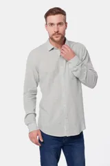 Camisa de lino color beige, de manga larga, con cuello clásico y bolsillo en el pecho.