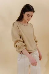 Blusa color beige de lino 100% con mangas balloon y detalle de tablón en el hombro. Tiene mangas largas con detalle de 2 pespuntes elásticos en contratono, el recurso del elástico es ideal para remangarse la manga generar más volumen. Calce recto, largo por arriba de la cadera.