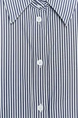 Camisa blanca de popelina de algodón, con cuello solapa y mangas largas con puños abotonados.