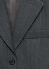Blazer gris con estampado de raya diplomática, cuello con solapa, cierre de botones en la parte delantera, manga larga con puños abotonados, hombreras y dos bolsillos de solapa en la parte delantera.