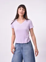 Remera de punto color lila con cuello en V y mangas cortas con terminación ondulada.