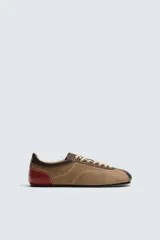 Zapato deportivo de piel color marrón claro con detalles en marrón oscuro y rojo. Presenta pespuntes en contraste, suela plana y cierre con cordones de colores. Colaboración especial Harry Lambert for Zara x Disney.
