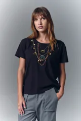 Remera negra de algodón con cuello redondo y mangas cortas. Presenta un estampado en el escote que simula un collar estilo boho con cuentas, borlas y dijes.