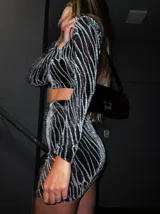 Conjunto de top manga larga y minifalda con estampado de líneas brillantes sobre tela transparente negra.