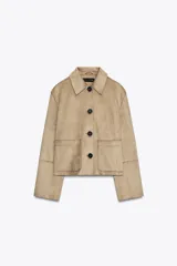 Cazadora color beige de cuello solapa y manga larga. Tiene bolsillos delanteros de plastrón, costuras marcadas y cierre frontal con botones.