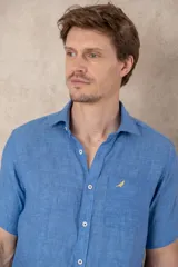 Camisa celeste de lino con manga corta, cuello clásico y corte recto.