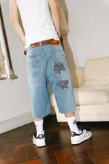 Bermuda baggy de jean celeste con lavado gastado en los laterales y bordados de letras chinas en negro y blanco.