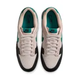 Zapatillas deportivas de baja caña en blanco con detalles en negro y verde, ideal para uso diario.