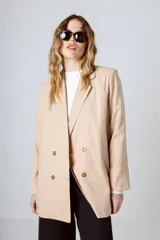 Blazer color beige con doble botonadura, solapas de muesca y corte holgado.