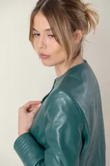 Campera azul de cuero ovino italiano, con cuello redondo, cierre frontal con broches ocultos, bolsillos laterales y detalle de capitoneado en puños y bolsillos.