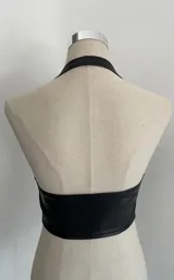 Top negro tipo halter de cuero sintético con escote en V y hebilla metálica en la cintura.