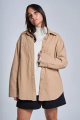 Sobrecamisa negra de gabardina con cuello camisero, cierre frontal con botones, mangas largas con puños abotonados y bolsillos de parche en el pecho.