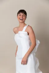 Vestido de tafeta blanco con un solo bretel y aplique de organza que forma un volado en la espalda.
