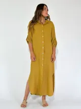 Vestido camisero largo color beige, con cuello clásico, abotonadura frontal completa, mangas 3/4 con trabilla y aberturas laterales.