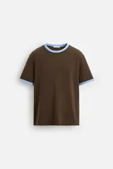 Camiseta marrón de corte regular, con cuello redondo y mangas cortas. Presenta ribete celeste en cuello y mangas.