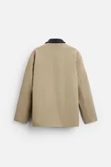 Parka negra de algodón con cuello solapa de cuero sintético, corte recto, acolchada, con bolsillos de parche y cierre frontal con botones.