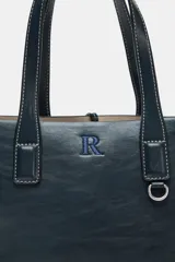 Bolso shopper azul marino con doble asa corta y correa larga de tela color crudo. Tiene detalle de pespuntes blancos y tira con anilla metálica.