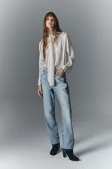 Jean de tiro alto de denim azul rígido con lavado claro localizado, bigotes y apliques laterales de strass.