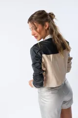 Chaqueta corta plateada de poliéster con terminaciones en beige y negro, cierre frontal y corte ajustado.
