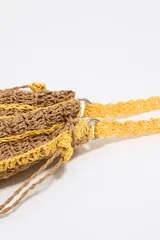 Bolso de mano tejido a crochet en color marrón con rayas horizontales amarillas, asa corta tejida a crochet color amarillo, cierre ajustable con cordones y borla colgante.