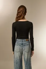 Body negro de poliéster con frunces, cuello en V profundo y manga larga.