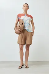 Blusa sin mangas con estampado floral en tonos celeste y naranja sobre fondo blanco. Presenta cuello redondo y corte recto.