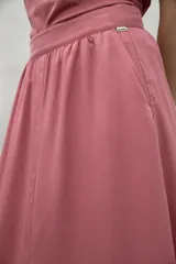 Falda midi color crema, de corte evasé, con cintura elastizada, bolsillos laterales y aberturas frontales y traseras.