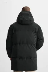Cazadora acolchada negra de tejido técnico, cuello alto con capucha ajustable, manga larga con puño interior elástico, bolsillos laterales y bolsillo interior. Cierre frontal con cremallera oculta y botones a presión.